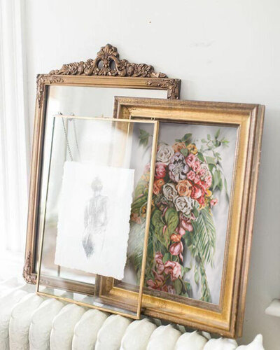 A collection of classical paintings in ornate gilded frames. Featured in a cottagecore home.