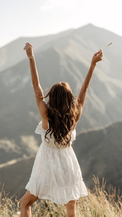 Woman with arms raised high, embracing empowerment and strength during menopause.