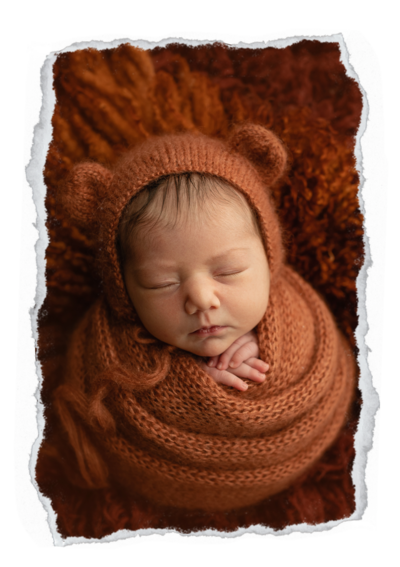 Baby wrapped as a bear on an orange rug.