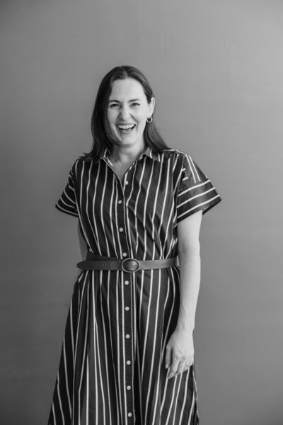 Black and White Brand Photo of Bridget Mary in a striped jumpsuit with a belt at the waist as she smiles to the camera.