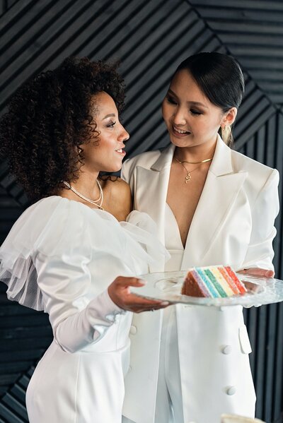 Lesbian brides holding a rainbow wedding cake
