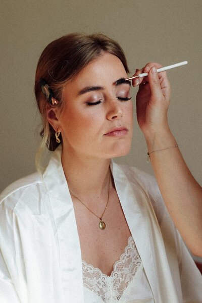 Make-up van bruid wordt aangebracht op ochtend van bruiloft, vastgelegd door trouwfotograaf in Nederland Linda Photography