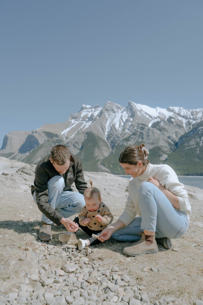 Family exploring with their child in the rocks at lake minnewanka during a family photo session.