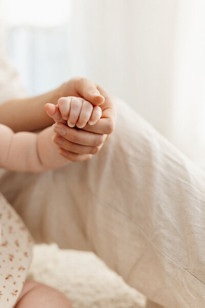 A close up of a mother holding her babys tiny hand showing the difference in size