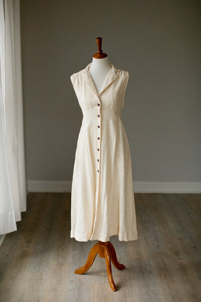 white dress in linen fabric with brown buttons going up the front of the dress