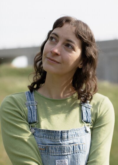 Heather smiles serenely in a field of tall grass, looking to the left.