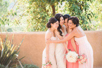 bride with her bridesmaids sharing a hug while waiting for the wedding ceremony to start at the Wedgewood Retreat in Riverside, California