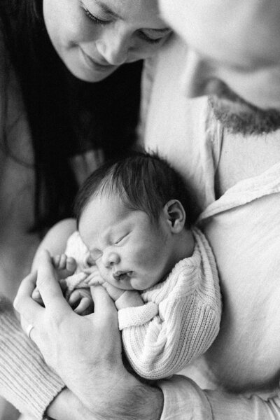 mum and toddler sitting on bed looking at baby