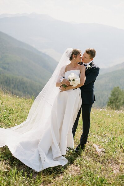 A Colorado bride and groom on the top of Vail mountain share a kiss