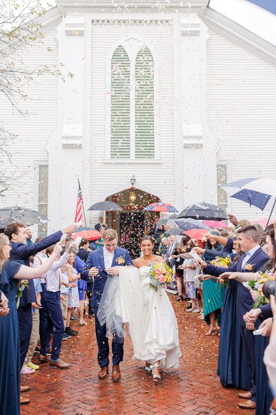 Bride and groom walking and holding hands through guests throwing confetti representing their endorsement of Christine Hazel Photography
