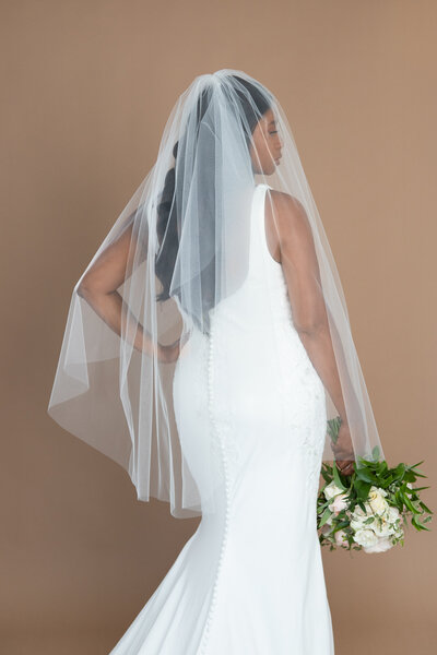 Bride wearing a two layered fingertip length veil and holding a white and blush bouquet