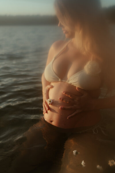 Zwangerschapsshoot in het water met bloemen