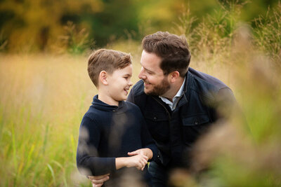 Dad with his son smiling at each other for their fall family photography session in Burlington, Ontario.