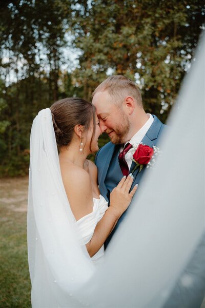 Romantic wedding photo of bride and groom going in for a kiss while the veil is sweeping in front of the camera in East Arkansas