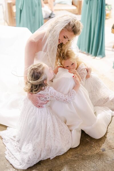 Bride seated and giving the two toddler flower girls a warm gentle embrace at one of the wedding venues in atlanta