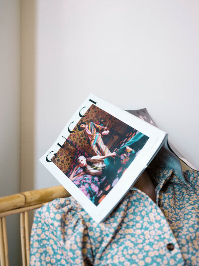 Commercial photography of model wearing floral shirt and Vogue magazine over her face