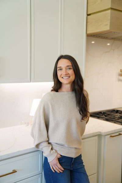 Woman standing in a bright modern kitchen, smiling confidently, representing personalized mineral testing and functional nutrition support.