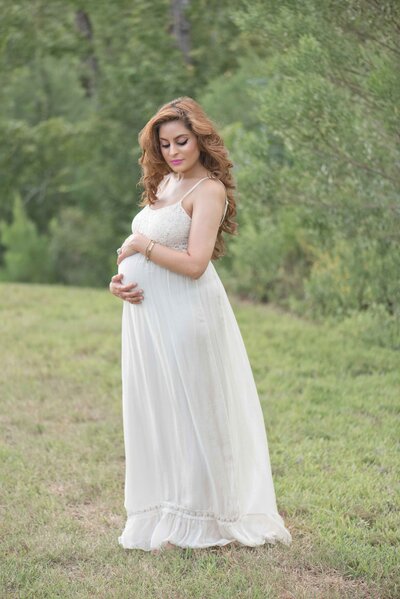 pregnant woman standing in field for her maternity photoshoot in houston texas