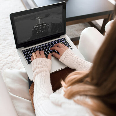 A woman sits comfortably on a couch, focused on her laptop, creating a cozy and productive atmosphere.
