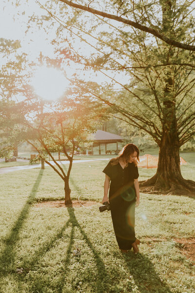 wedding photographer standing in park holding camera and looking down at it