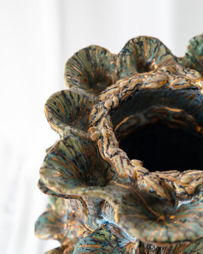 Close-up shot of a detailed, hand-painted ceramic sculpture, showcasing the craftsmanship of Gerda Satunas.