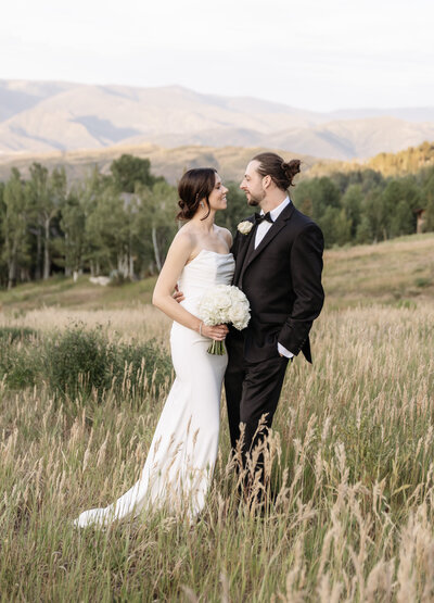A bride and groom glancing at each other on their wedding day, in Aspen, Colorado shot by Kelly Elizabeth Photography.