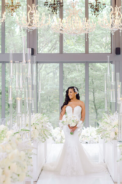 Bride in a strapless, beaded gown holding a cascading bouquet of white phalaenopsis orchids, roses, and snapdragons, designed by Wells Design Co.