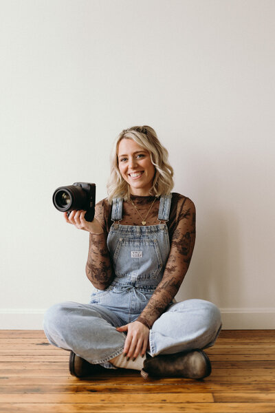 Vermont wedding photographer Grace sitting on floor holding camera