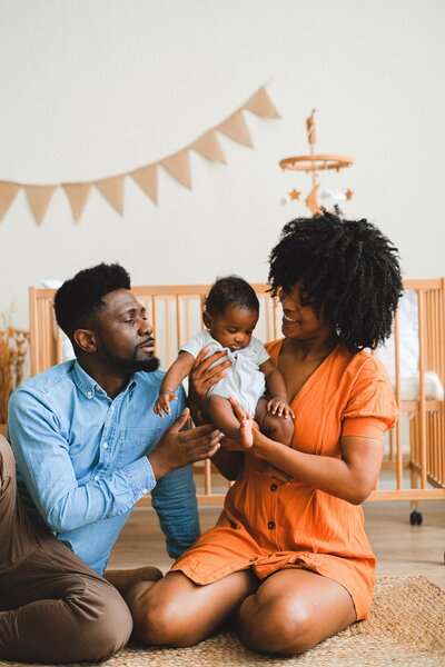 Black family mother and father with baby in nursery