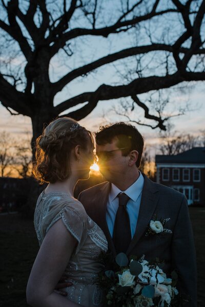 Bride and groom in a gown and suit staring into each other’s eyes outdoors at sun down.