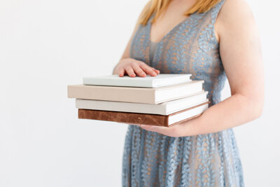 Woman holding a stack of photo albums at Tiffany Hix Photography portrait studio in Boise, ID