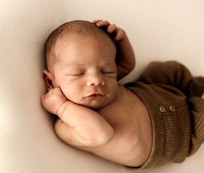 Ruua Hamdan Photography (Altrincham/Manchester, UK): A sleeping baby wearing a brown bonnet.