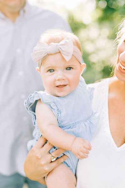 Blonde baby girl with bow smiling at camera