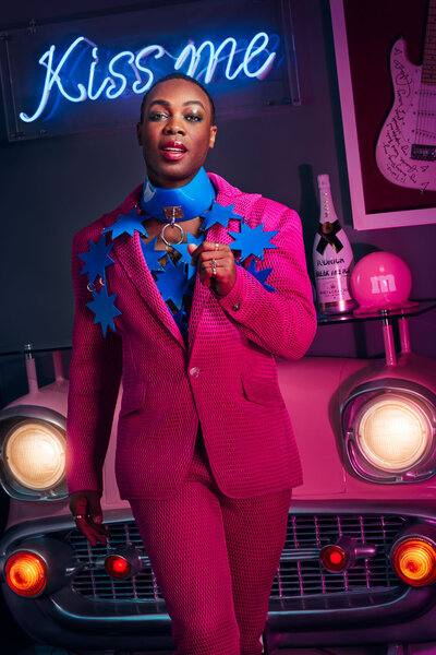 Fashion-forward portrait of Todrick Hall in a bright pink suit, posing confidently, shot by Ylva Erevall.