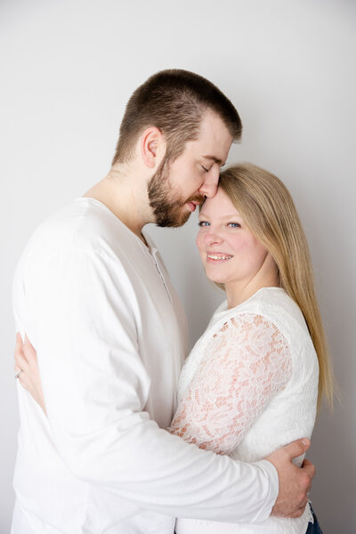 Husband snuggling into his wife at their home while she smiles at the camera in Beavercreek, Ohio.