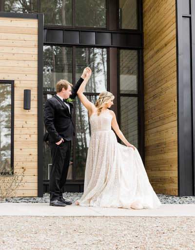 Bride and groom dancing in front of a wood and glass window building
