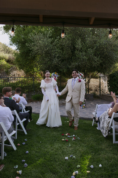 Regan and Yered walking down the aisle together at their backyard wedding.