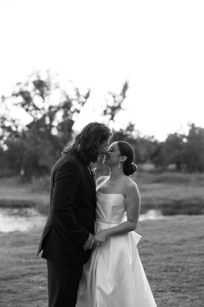 An Austin-based wedding photographer captures a beautiful moment of the bride and groom kissing in front of a serene pond.