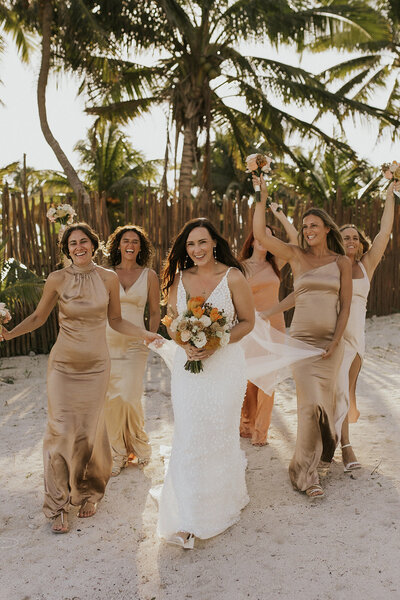 bride and her bridesmaids laughing on the beach