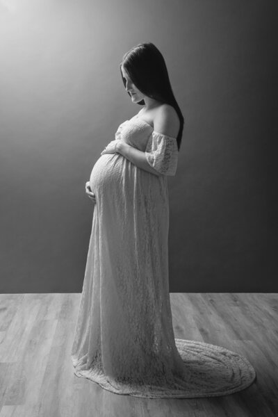pregnant woman standing in a long dress  in a studio