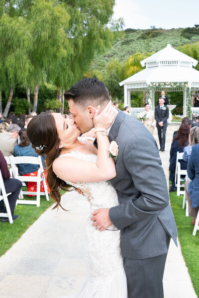 bride and groom kiss at end of aisle at Moorpark Country Club