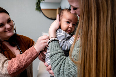 Charis Koenig holds newborn at postpartum exam