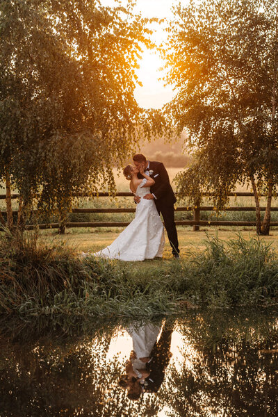 Bride and groom sharing a kiss in golden hour sunlight at Caswell House