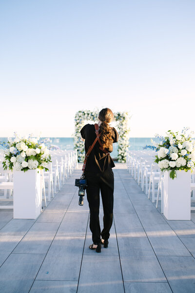 an images taken from behind cape cod wedding photographer meghan lynch as she is taking a photo of a floral arch at wychmere dune