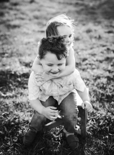 A joyful moment of two children sharing a playful embrace, captured in black and white by Leslie Q Photography