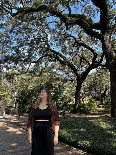 Business owner standing outdoors under large oak trees, representing visibility and credibility in online business