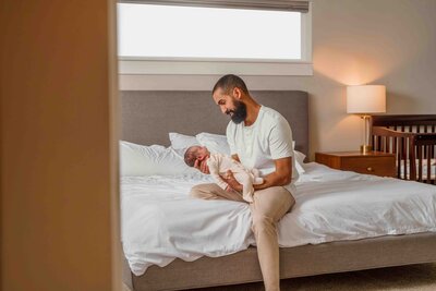 Proud Renton Dad Holds newborn baby in natural light during his lifestyle in-home newborn session