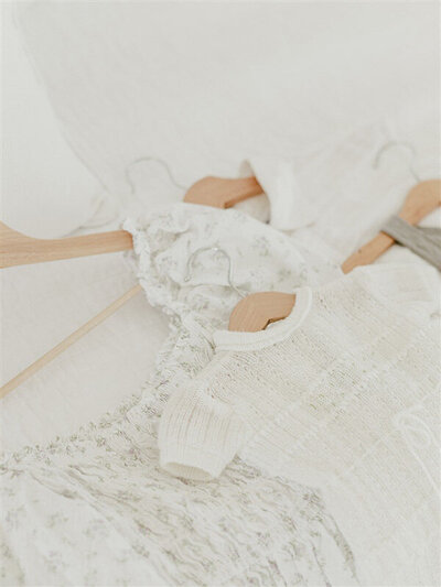 A flat lay of soft, neutral baby clothing arranged for a session, styled by Kansas City photographer Meredith Maag as part of her wardrobe service.