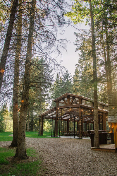 Large outdoor timber structure surrounded by nature, The Valley Weddings, a rustic and majestic wedding venue in Westerose, Alberta, featured on the Brontë Bride Vendor Guide.