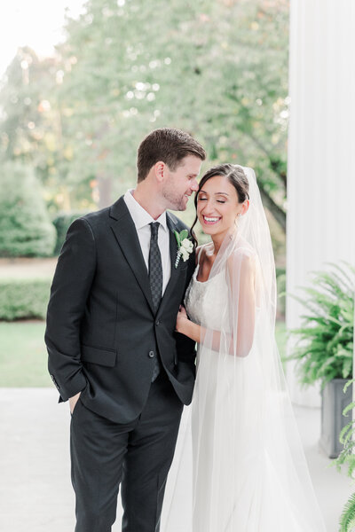 bride and groom snuggled on the porch of burr mansion